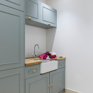 Photo of a small traditional single-wall separated utility room in London with a belfast sink, shaker cabinets, green cabinets, wood worktops, grey walls, slate flooring, beige floors and brown worktops.