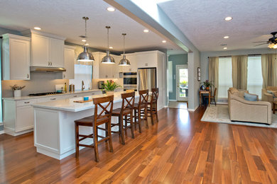 Inspiration for a mid-sized modern medium tone wood floor eat-in kitchen remodel in Houston with an undermount sink, shaker cabinets, white cabinets, quartz countertops, gray backsplash, subway tile backsplash, stainless steel appliances and an island