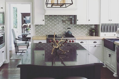 Large beach style u-shaped dark wood floor and brown floor open concept kitchen photo in Orange County with a farmhouse sink, shaker cabinets, white cabinets, marble countertops, green backsplash, ceramic backsplash, stainless steel appliances and an island