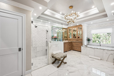 Example of a large trendy white floor and tray ceiling bathroom design in Raleigh with medium tone wood cabinets, a hinged shower door and a built-in vanity