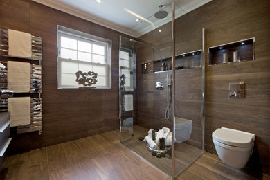 This is an example of a contemporary bathroom in London with a curbless shower, a wall-mount toilet, brown tile and wood-look tile.