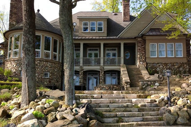 Design ideas for a large traditional three-storey beige exterior in Grand Rapids with stone veneer and a clipped gable roof.