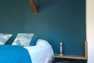 Imagen de dormitorio principal moderno grande con paredes azules, suelo marrón y vigas vistas
