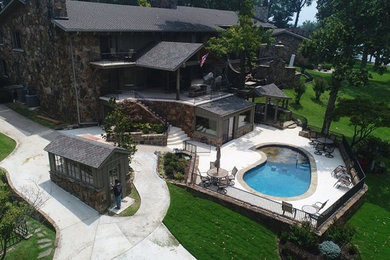 Inspiration for a huge rustic backyard concrete patio kitchen remodel in Other with a roof extension