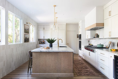 Example of a large transitional single-wall laminate floor and brown floor kitchen design in San Diego with an undermount sink, shaker cabinets, white cabinets, quartz countertops, white backsplash, quartz backsplash, stainless steel appliances and white countertops
