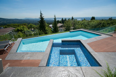 Contemporary backyard custom-shaped infinity pool in Vancouver with a hot tub and decking.