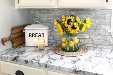 Farmhouse kitchen photo in Seattle with laminate countertops and brick backsplash