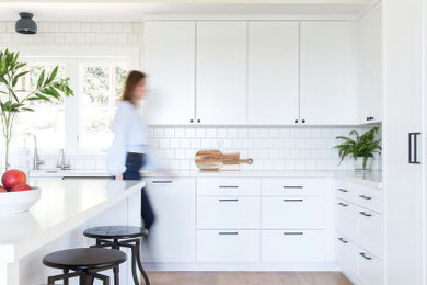 Inspiration for a large transitional l-shaped beige floor kitchen remodel in San Francisco with shaker cabinets, white cabinets, white backsplash, subway tile backsplash, an island and white countertops