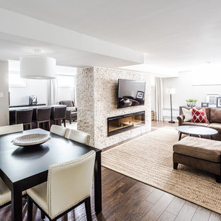 モントリオールの広いトランジショナルスタイルのLDKの画像 (グレーの壁、濃色無垢フローリング、横長型暖炉、石材の暖炉まわり、茶色い床)