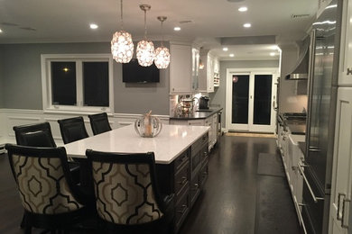 Large transitional galley dark wood floor eat-in kitchen photo in New York with a farmhouse sink, recessed-panel cabinets, black cabinets, quartz countertops, white backsplash, subway tile backsplash, stainless steel appliances and an island