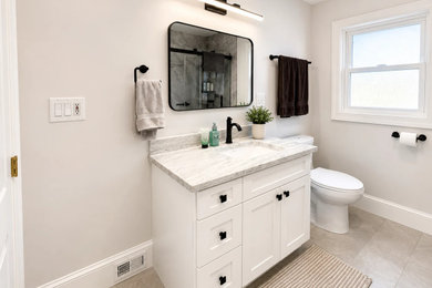 Small transitional 3/4 gray tile laminate floor, gray floor and single-sink bathroom photo in Charlotte with shaker cabinets, white cabinets, a one-piece toilet, gray walls, granite countertops, gray countertops and a built-in vanity