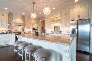 Design ideas for a large traditional l-shaped kitchen in Philadelphia with a farmhouse sink, subway tile splashback, stainless steel appliances, dark hardwood floors, brown floor, white splashback, raised-panel cabinets, white cabinets, granite benchtops, with island and white benchtop.