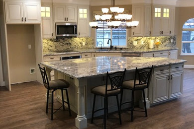 Inspiration for an expansive traditional l-shaped eat-in kitchen in Sacramento with a double-bowl sink, white cabinets, granite benchtops, grey splashback, stone slab splashback, stainless steel appliances, medium hardwood floors, with island, brown floor and grey benchtop.