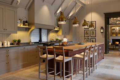 Design ideas for a medium sized classic single-wall enclosed kitchen in Surrey with a belfast sink, shaker cabinets, beige cabinets, granite worktops, white splashback, metro tiled splashback, black appliances, limestone flooring, an island, grey floors, grey worktops and a timber clad ceiling.