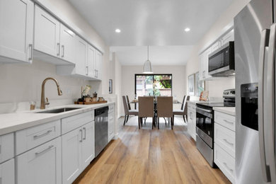 Eat-in kitchen - small transitional galley vinyl floor and brown floor eat-in kitchen idea in San Francisco with an undermount sink, recessed-panel cabinets, white cabinets, quartz countertops, multicolored backsplash, quartz backsplash, stainless steel appliances, no island and multicolored countertops