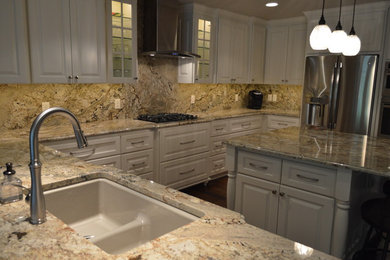 This is an example of a large traditional u-shaped eat-in kitchen in Milwaukee with a double-bowl sink, stone slab splashback, stainless steel appliances, with island, raised-panel cabinets, white cabinets, granite benchtops, multi-coloured splashback, dark hardwood floors, brown floor and multi-coloured benchtop.