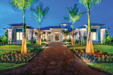 Photo of a large contemporary two-storey stucco grey house exterior in Miami with a hip roof and a metal roof.