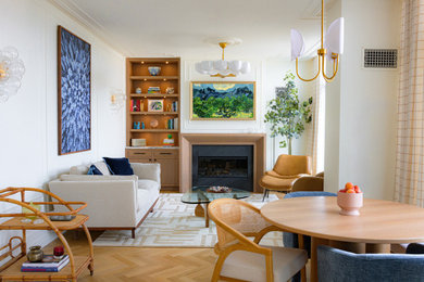 Example of a mid-sized transitional open concept light wood floor living room design in Providence with white walls, a standard fireplace, a wood fireplace surround and a concealed tv