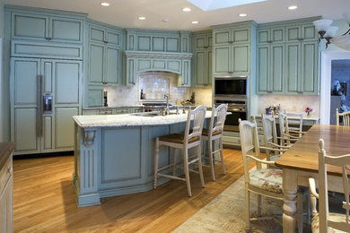 Design ideas for a traditional l-shaped eat-in kitchen in Minneapolis with blue cabinets, granite benchtops, white splashback, an undermount sink, raised-panel cabinets, stone tile splashback and panelled appliances.