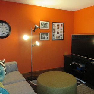 Photo of a small midcentury walk-out basement in Denver with orange walls, concrete flooring, a wood burning stove, a stone fireplace surround and brown floors.