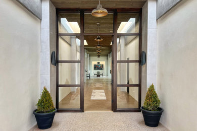 Modelo de puerta principal moderna grande con paredes grises, suelo de cemento, puerta simple, puerta de madera en tonos medios, suelo marrón y madera