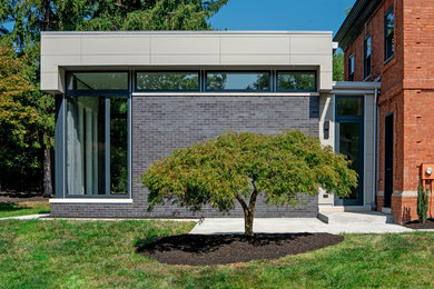 Mid-sized minimalist black one-story brick exterior home photo in Other