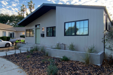 Inspiration for a mid-century modern beige one-story metal exterior home remodel in Los Angeles with a shingle roof and a black roof