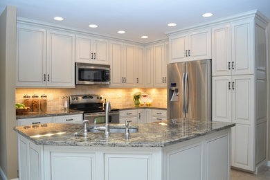 Example of a classic porcelain tile eat-in kitchen design in Baltimore with an undermount sink, raised-panel cabinets, white cabinets, granite countertops, beige backsplash, stainless steel appliances and two islands