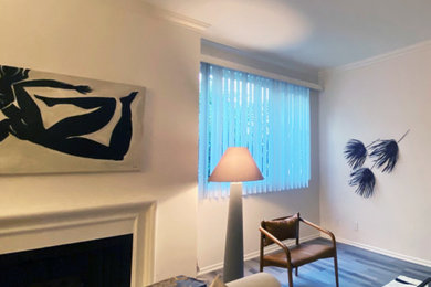 Mittelgroßes, Offenes Modernes Wohnzimmer mit weißer Wandfarbe, Laminat, Kamin, verputzter Kaminumrandung, freistehendem TV und grauem Boden in Los Angeles