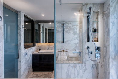 Inspiration for a mid-sized contemporary master wet room bathroom in Sydney with furniture-like cabinets, dark wood cabinets, a wall-mount toilet, white tile, marble, multi-coloured walls, marble floors, a vessel sink, marble benchtops, multi-coloured floor, an open shower and white benchtops.