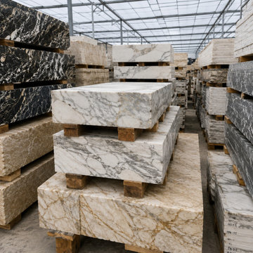 Premium marble and granite slabs neatly stacked in a spacious warehouse, showcas
