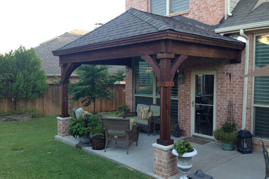 Small arts and crafts backyard patio in Dallas with concrete slab and a roof extension.
