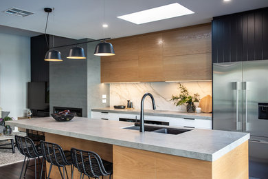 This is an example of a mid-sized contemporary galley kitchen pantry in Adelaide with a double-bowl sink, black cabinets, concrete benchtops, white splashback, stone slab splashback, black appliances, dark hardwood floors, with island, brown floor and grey benchtop.