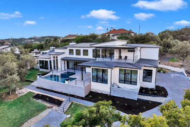 Example of a huge trendy white two-story stone exterior home design in Austin with a metal roof and a gray roof