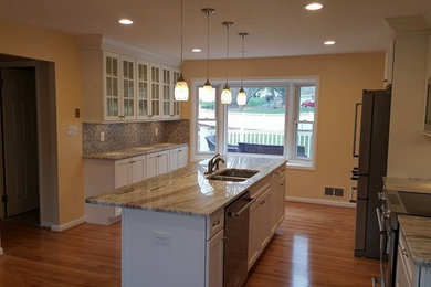 Large trendy single-wall medium tone wood floor kitchen photo in Baltimore with shaker cabinets, white cabinets, multicolored backsplash, an island, granite countertops, mosaic tile backsplash, a double-bowl sink and stainless steel appliances