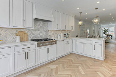 Example of a mid-sized minimalist l-shaped light wood floor eat-in kitchen design in DC Metro with an undermount sink, beaded inset cabinets, white cabinets, quartz countertops, white backsplash, marble backsplash, stainless steel appliances, a peninsula and white countertops