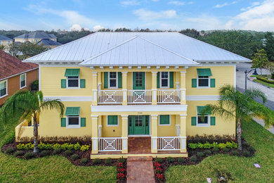 Inspiration for a large coastal yellow two-story stucco exterior home remodel in Orlando with a metal roof