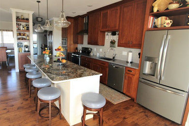 Kitchen - traditional medium tone wood floor kitchen idea in Other with an undermount sink, shaker cabinets, brown cabinets, granite countertops, gray backsplash, ceramic backsplash, stainless steel appliances and an island