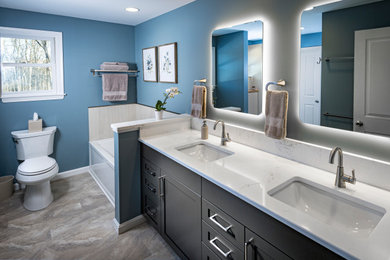 Example of a large transitional vinyl floor, multicolored floor and double-sink bathroom design in Other with shaker cabinets, brown cabinets, a two-piece toilet, blue walls, an undermount sink, quartz countertops, a hinged shower door, white countertops and a built-in vanity