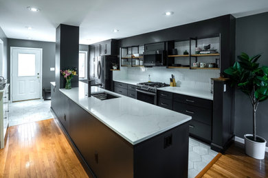 Mid-sized contemporary galley eat-in kitchen in Other with a single-bowl sink, shaker cabinets, black cabinets, quartz benchtops, white splashback, ceramic splashback, stainless steel appliances, ceramic floors, with island, grey floor and white benchtop.