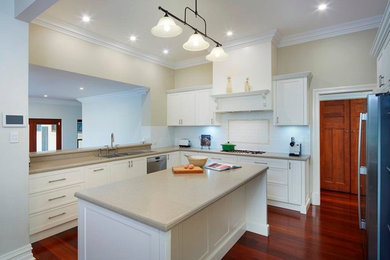Inspiration for a traditional u-shaped kitchen in Perth with a double-bowl sink, shaker cabinets, white cabinets, solid surface benchtops, white splashback, subway tile splashback, stainless steel appliances, dark hardwood floors and brown floor.