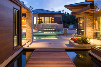 Inspiration for a large contemporary backyard deck in San Francisco with a water feature and a roof extension.