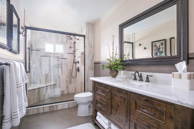 Design ideas for a mid-sized country bathroom in San Diego with recessed-panel cabinets, distressed cabinets, an alcove shower, brown tile, ceramic tile, beige walls, ceramic floors, an undermount sink and marble benchtops.