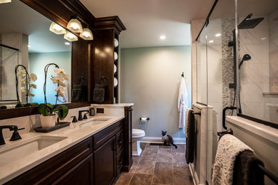 Example of a large classic master white tile and marble tile porcelain tile, brown floor and double-sink double shower design in Philadelphia with raised-panel cabinets, brown cabinets, a two-piece toilet, blue walls, a drop-in sink, quartz countertops, a hinged shower door, white countertops and a built-in vanity