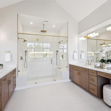 Spa primary bath with walnut dual vanities and frameless glass shower