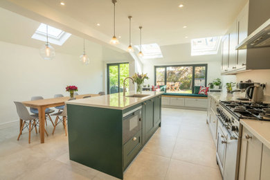 This is an example of a large traditional single-wall open plan kitchen in Sussex with shaker cabinets, green cabinets, quartzite benchtops, with island and white benchtop.