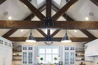 Inspiration for a country dark wood floor and brown floor kitchen remodel in Milwaukee with a farmhouse sink, recessed-panel cabinets, white cabinets, soapstone countertops, white backsplash, ceramic backsplash, stainless steel appliances and an island
