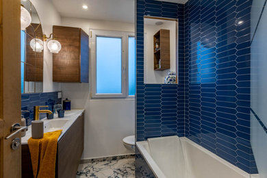 Cette image montre une petite salle de bain principale et blanche et bois design en bois foncé avec un placard à porte affleurante, une baignoire en alcôve, un carrelage bleu, des carreaux de céramique, un mur blanc, un sol en marbre, un plan vasque, un plan de toilette en surface solide, un sol bleu, un plan de toilette blanc, une fenêtre, meuble simple vasque, meuble-lavabo suspendu et WC suspendus.