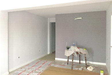 Cette image montre un petit salon minimaliste ouvert avec un mur gris et parquet clair.
