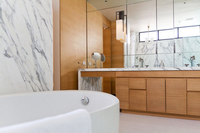 Photo of a large contemporary master bathroom in New York with flat-panel cabinets, medium wood cabinets, a freestanding tub, gray tile, white tile, stone slab, grey walls, mosaic tile floors, an undermount sink, quartzite benchtops and grey floor.
